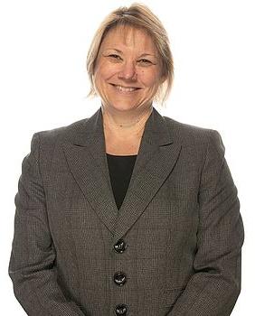 Gayla Rogers stands in front of at white background, smiling at the camera.